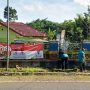 Sertu Ramlan, anggota Koramil 414-02/Manggar Melaksanakan Gotong Royong di Area Sekitar Kantor Desa Simpang Tiga bersama Perangkat Desa